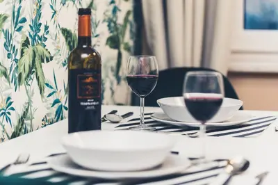 a table with a bottle of wine and two glasses at FatCat Apartments in Kraków