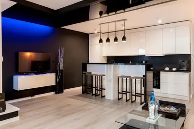 a kitchen with white cabinets and a bar with stools at Diamonds Apartment in Kraków