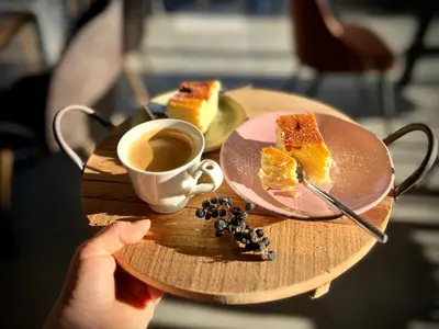 a person holding a tray with a plate of cake and a cup of coffee at Zagroda na Pacanach in Iwkowa