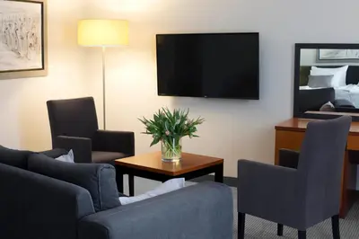 a hotel room with a couch and chairs and a tv at Benefis Boutique Hotel in Kraków
