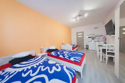 two beds in a room with a kitchen and a table at Apartament Franka in Oświęcim