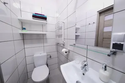 a white bathroom with a toilet and a sink at Apartament Franka in Oświęcim
