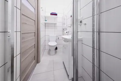 a white bathroom with a toilet and a sink at Apartament Franka in Oświęcim