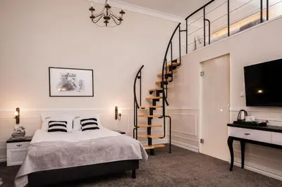 a bedroom with a bed and a spiral staircase at Imagine Apartments in Kraków