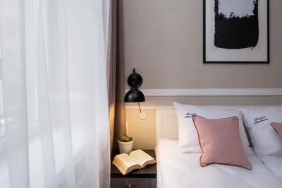 a bedroom with a bed with white sheets and pink pillows at Imagine Apartments in Kraków
