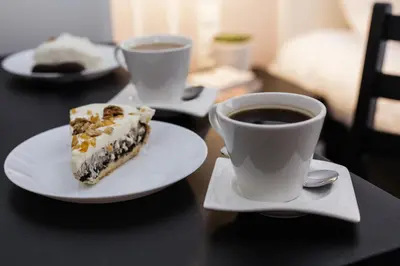 a piece of cake and two cups of coffee on a table at Imagine Apartments in Kraków