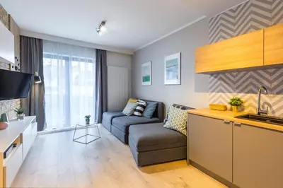 a living room with a couch and a kitchen at Wawel Cracow Old City Apartments - Friendhouse Apartments in Kraków