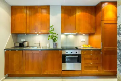 a kitchen with wooden cabinets and a sink at Wawel Cracow Old City Apartments - Friendhouse Apartments in Kraków
