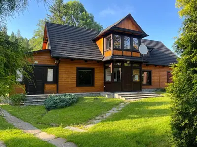 a wooden house with a black roof at Willa Stróża in Myślenice