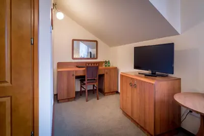 a room with a desk with a television on a wooden cabinet at Hotel - Karczma Klimtówka in Wolbrom