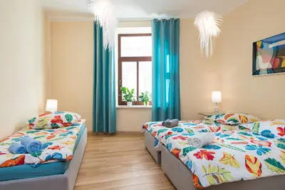 two beds in a bedroom with blue curtains and a window at Style4rent Apartament Kazimierz in Kraków