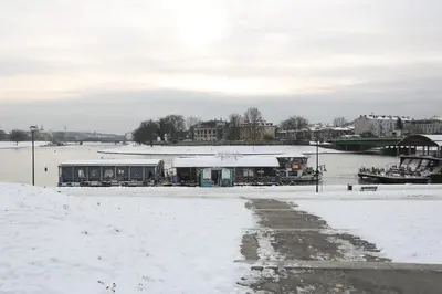 a building in the snow next to a body of water at Cheerful Air Conditioned Apartment with mezzanine and Parking - Old Town in Kraków