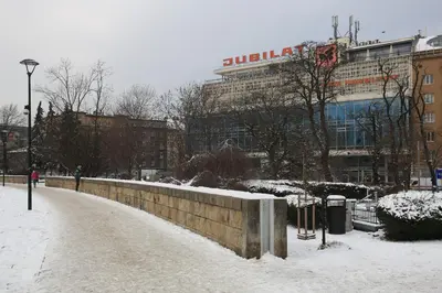 a snow covered street in front of a building at Cheerful Air Conditioned Apartment with mezzanine and Parking - Old Town in Kraków