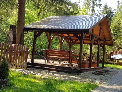 a wooden gazebo with a bench in a park at Domek Krasnal in Juszczyn