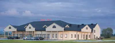 a large building with cars parked in front of it at Hotel Graal Targowisko in Targowisko