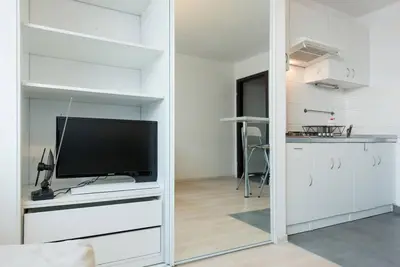a living room with a flat screen tv and a kitchen at Studio Aleja Pokoju in Kraków