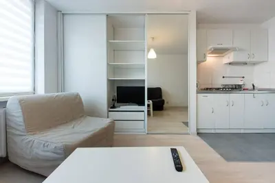 a living room with a white couch and a kitchen at Studio Aleja Pokoju in Kraków