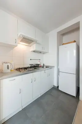 a kitchen with white cabinets and a white refrigerator at Studio Aleja Pokoju in Kraków
