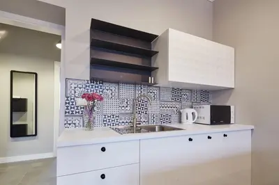 a white kitchen with a sink and a tile wall at PlayRoom II Apartment in Kraków