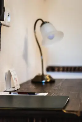 a desk with a lamp on top of a table at Hotel Pod Kogutkiem in Krzywaczka