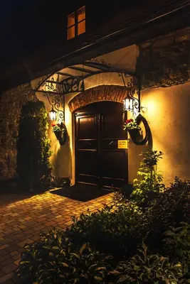 an entrance to a house with a door at night at Hotel Pod Kogutkiem in Krzywaczka