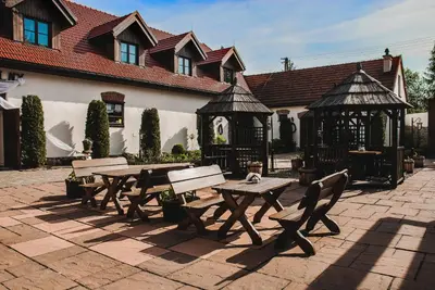 a picnic table and benches in front of a building at Hotel Pod Kogutkiem in Krzywaczka