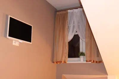 a window with a white curtain and a television at Carmen Apartment in Kraków