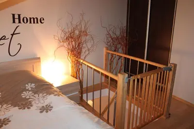 a bedroom with a bed and a staircase with a home sign at Carmen Apartment in Kraków