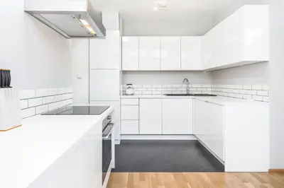 a white kitchen with white cabinets and a sink at Apartment Zegadłowicza in Kraków