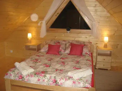 a bed with red pillows in a wooden room at Domek drewniany simonka zawoja in Zawoja