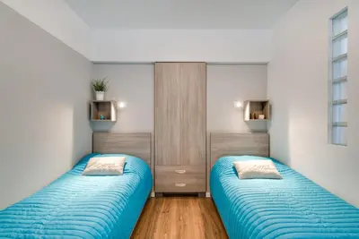 two beds in a room with blue sheets at Apartment Masarska in Kraków