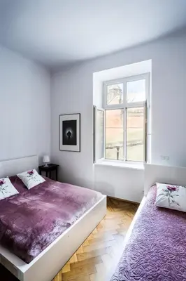 two beds in a white room with a window at Apartment Bernardynska in Kraków