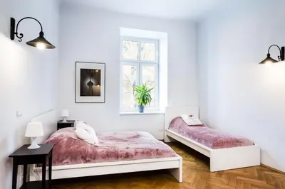 a white bedroom with two beds and a window at Apartment Bernardynska in Kraków