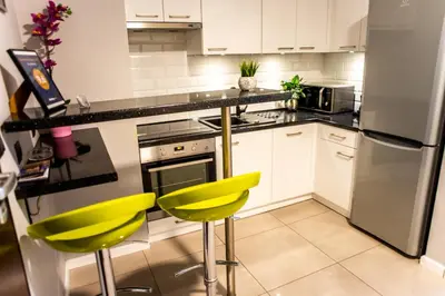 a kitchen with white cabinets and yellow chairs at Przy Mocaku in Kraków