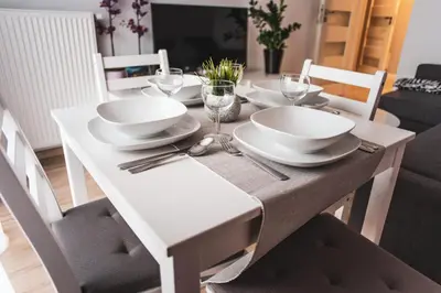 a white dining room table with plates and wine glasses at Przy Mocaku in Kraków