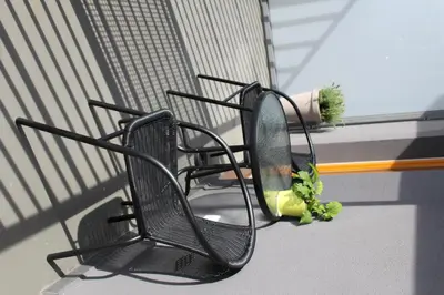 two black chairs sitting on a balcony with a plant at Przy Mocaku in Kraków