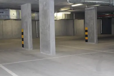 an empty parking lot with concrete columns in a parking garage at Przy Mocaku in Kraków