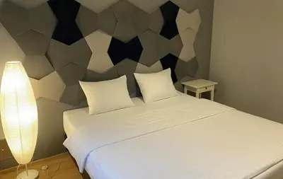 a bedroom with a white bed with a geometric headboard at Apartament Bielany Kraków in Kraków