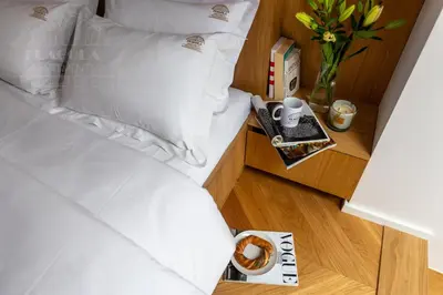 a bed with white pillows and a table with a vase of flowers at Fragola Apartments Old Town in Kraków
