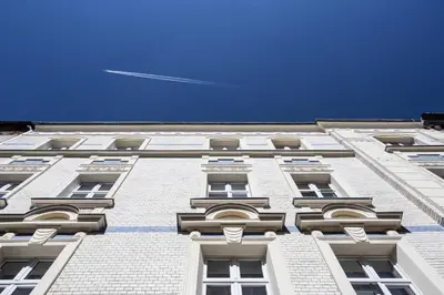 a tall white building with windows and a blue sky at Zulian Aparthotel by Artery Hotels in Kraków