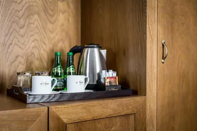 a shelf with bottles and cups and a coffee maker at Zulian Aparthotel by Artery Hotels in Kraków