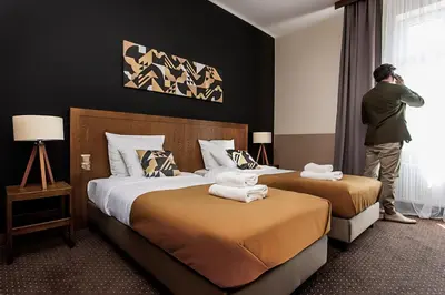 a man standing in a hotel room with two beds at Zulian Aparthotel by Artery Hotels in Kraków