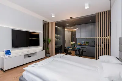 a bedroom with a large white bed with a flat screen tv at Apartament Mateo Inn in Kraków