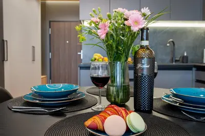 a table with a glass of wine and a vase of flowers at Apartament Mateo Inn in Kraków
