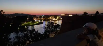a person sitting on a ledge looking at a river at Apartment Łobzowska in Kraków