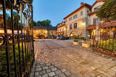a cobblestone street in front of a wrought iron gate at Folwark Stara Winiarnia in Mszana Dolna