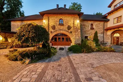 a large stone house with a brick driveway at Folwark Stara Winiarnia in Mszana Dolna