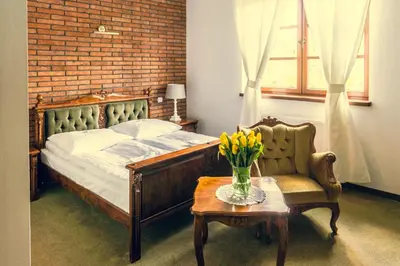 a bedroom with a bed and a chair and a table at Folwark Stara Winiarnia in Mszana Dolna
