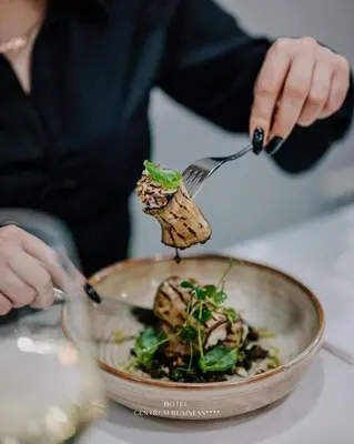 a person holding a fork and a bowl of food at Hotel Centrum Business in Kraków