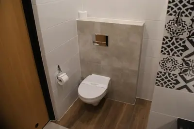 a bathroom with a toilet and a toilet paper dispenser at Friendly Apartments - Krakow in Kraków